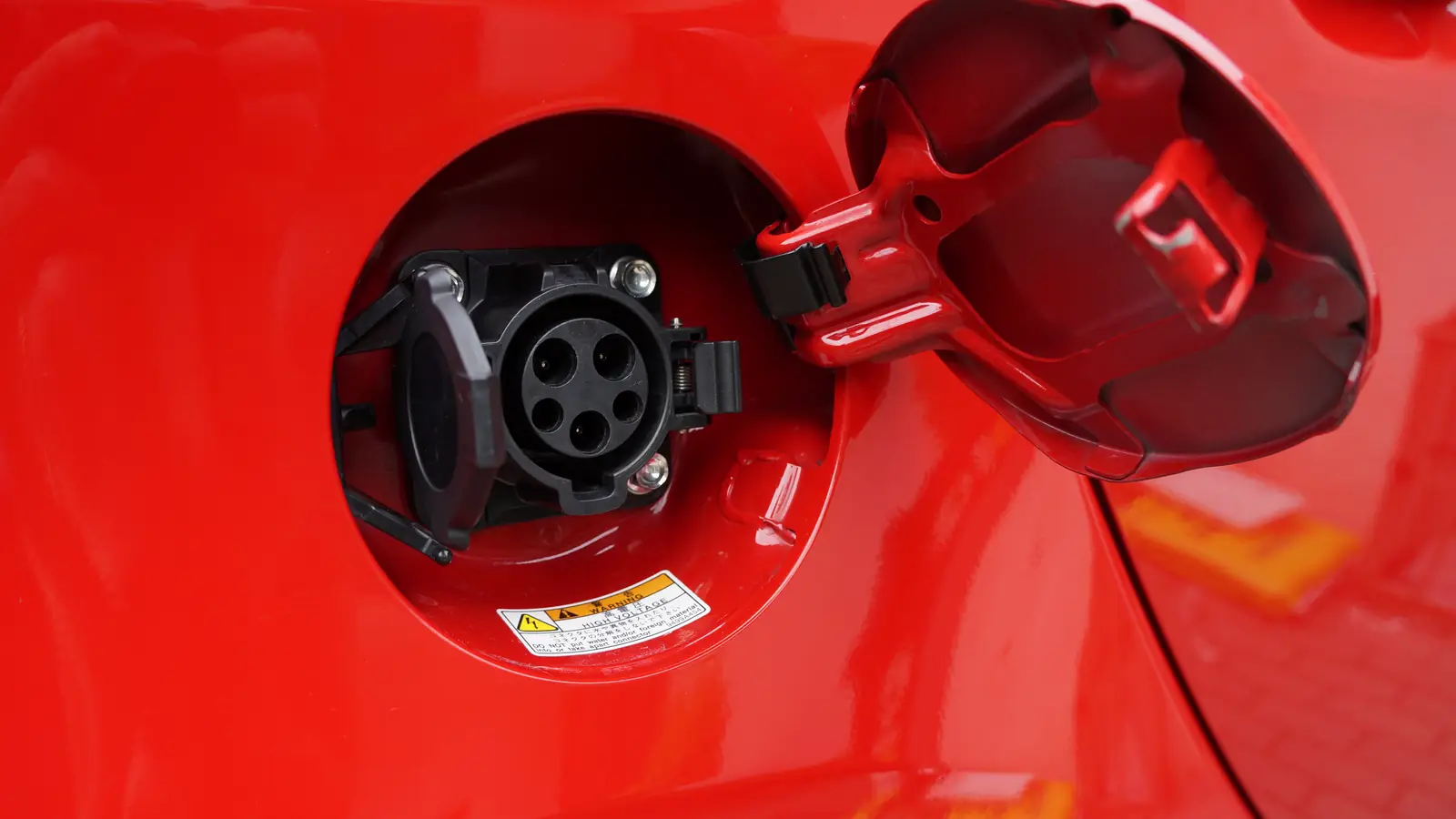 Open Level 2 (J1772) charging port on the red side of an electric car
