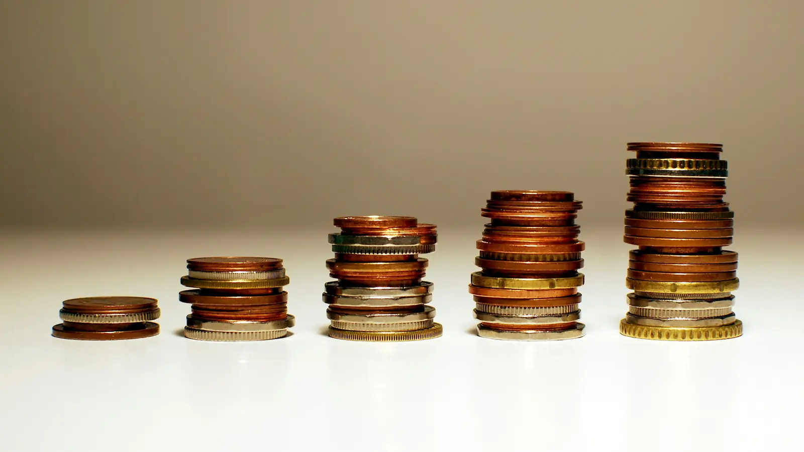 Stacks of coins getting taller from left to right, like a price going up